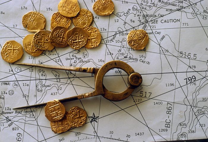 Caption 2- Bronze navigational divider displayed with a group of two escudos from the Santa Fe De Bogata mint. -1715 Fleet