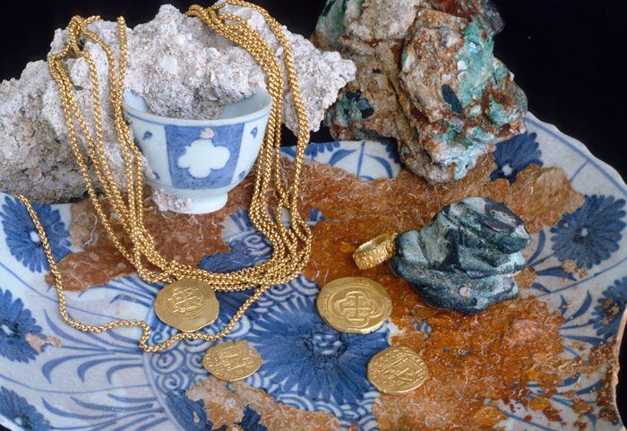 Caption 16- Display of fine porcelain, chains and gold escudos from the Mexico and Lima mints. Also pictured is a gold ring near a clump of silver reales fused together by the action of seawater on the surface of the silver coins. -1715 Fleet