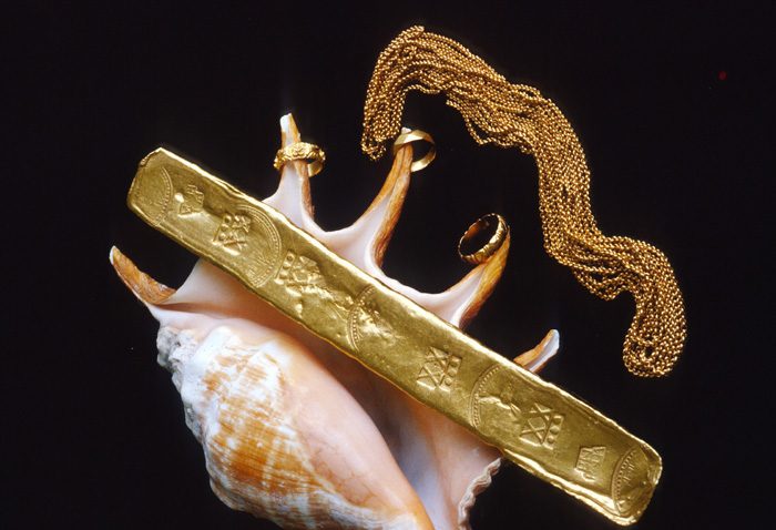 Caption 30- A Colombian gold bar of 20.75 kt struck at the Peña-Randa foundry 1621-22. A heavy gold chain and delicate gold rings attached to the fingers of a conch shell. -Recovered from the Florida Keys wreck site of Nuestra Señora de Atocha - 1622.