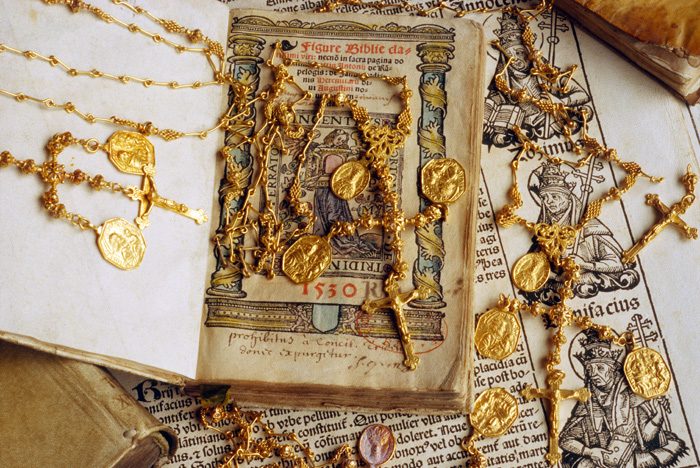 Caption 32- Gold religious artifacts including crucifixes and medals displayed on a sixteenth century Bible. -1715 Fleet