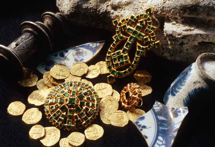 Caption 33- A gold cross, brooch and ring inset with Colombian emeralds, surrounded by Colombian two escudos. -Maravillas 1656